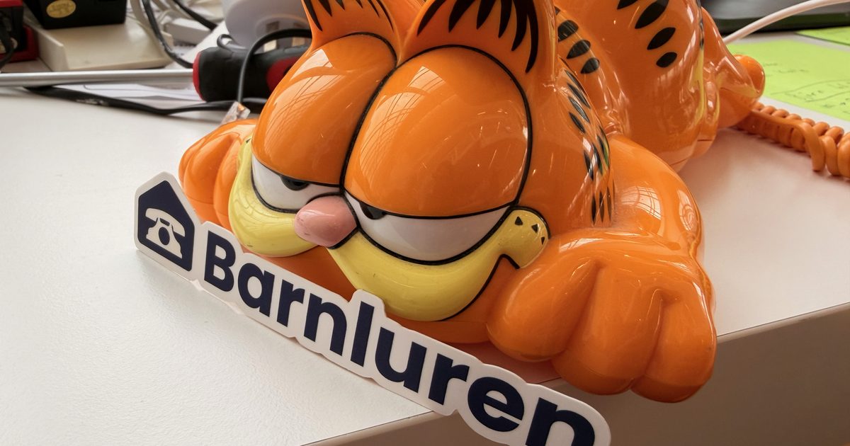 An orange vintage Garfield telephone lying on a table with its cord in view
